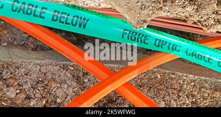 Wohnstraße Nahaufnahme Arbeiten im Gange installieren High-Speed-ultraschnelle Glasfaser-Breitbandkabel grünen Kunststoff Warnband Bürgersteig Graben UK Stockfoto