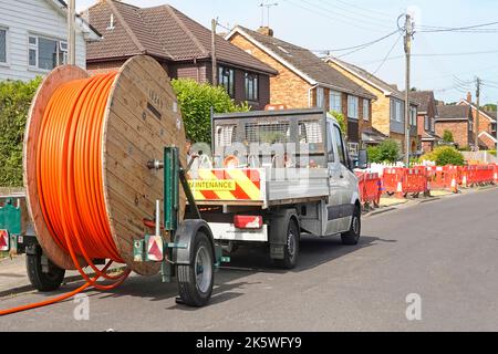 Kabeltrommel Anhänger Auftragnehmer abholen LKW neben Bürgersteig Graben arbeiten an Glasfaser-Breitband-Straßenarbeiten in Dorf Wohnstraße Essex UK Stockfoto