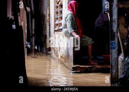 Jakarta, Indonesien. 10. Okt, 2022. Menschen sahen warten, bis das Flutwasser während der Nachwirkungen zurückgeht. Durch das Überlaufen des Ciliwung River wurden 68 Gebiete in Jakarta von Überschwemmungen heimgesucht. Kredit: SOPA Images Limited/Alamy Live Nachrichten Stockfoto