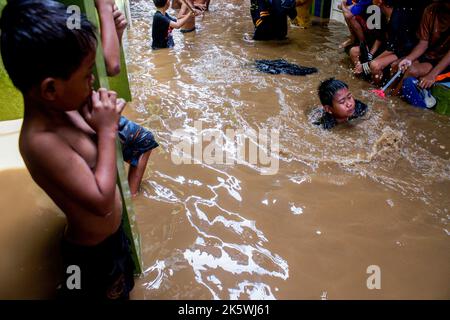 Jakarta, Indonesien. 10. Oktober 2022. Die Kinder sahen, wie sie in der Folgezeit ins Wasser spielten. Durch das Überlaufen des Ciliwung River wurden 68 Gebiete in Jakarta von Überschwemmungen heimgesucht. Kredit: SOPA Images Limited/Alamy Live Nachrichten Stockfoto