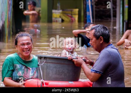 Jakarta, Indonesien. 10. Oktober 2022. Die Bewohner sahen, wie sie ein Baby nach der Katastrophe vor Überschwemmungen retteten. Durch das Überlaufen des Ciliwung River wurden 68 Gebiete in Jakarta von Überschwemmungen heimgesucht. Kredit: SOPA Images Limited/Alamy Live Nachrichten Stockfoto