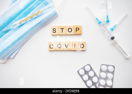 Stoppen Sie die Inschrift des Coronavirus. Vorbereitung für die Impfung gegen covid-19. Spritze, Impfstoff, Pillen, medizinische Maske Stockfoto