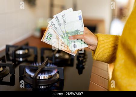 Zählen von Euro-Banknoten in der Nähe des brennenden Gasofens Stockfoto