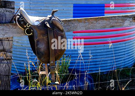 Sattel auf Zaun grobes Holz mit amerikanischer Flagge Americana Stockfoto