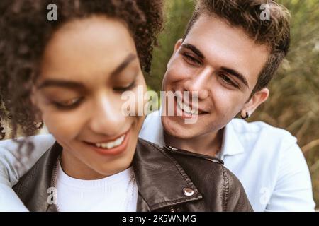 Porträt eines romantischen internationalen jungen Paares umarmt sich im Freien, liebevoll lächelnd multiethnischen Freund und Freundin flirten zusammen, interracial relat Stockfoto