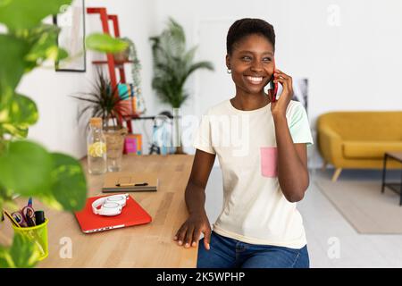 Porträt einer trendigen afroamerikanischen Frau, die zu Hause ein Mobiltelefon benutzt Stockfoto
