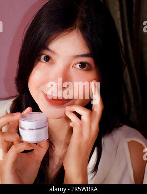 Schöne asiatische Frau hält eine Schönheit Hautpflege Creme Produkt mit Nahaufnahme Porträt Stockfoto