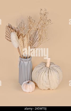 Herbstdeko mit gestricktem beigen Kürbis im Boho-Stil und getrockneten Blumen Stockfoto