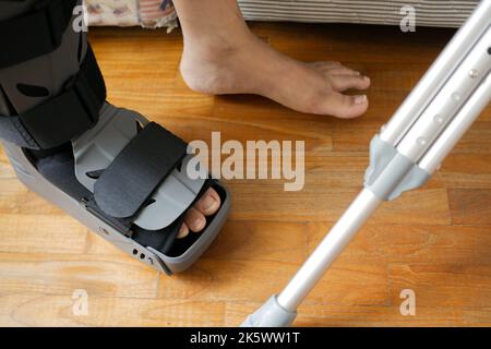 Frauen gebrochene Füße mit einem grauen Kunststoffstiefel Knöchelschutz Verletzung Schutz Stiefel Stockfoto