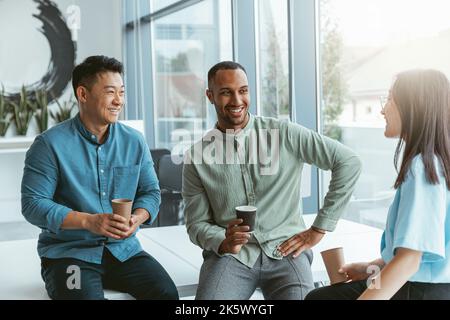 Lächelnde Gruppe multiethnischer Kollegen, die während der Pause Kaffee trinken und sich unterhalten Stockfoto