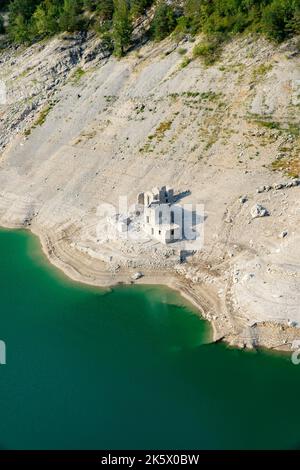 Eine vertikale Aufnahme einer ruinierten Burg an einem Sandstrand mit türkisfarbenem Meer Stockfoto