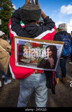 Ein Protestler trägt ein Plakat auf dem Rücken von Mahsa Amin während der Demonstration auf dem Malieveld, Den Haag. Die Iraner und ihre Anhänger versammelten sich in Den Haag Hunderte von Menschen, um die Iraner zu unterstützen, die auf den Straßen des Iran protestierten. Sicherheitskräfte im Iran haben Demonstranten nach der Verhaftung und dem plötzlichen Tod des 22-jährigen Mahsa Amin und des 17-jährigen Nika Shakarami niedergeschlagen; sie wurden wegen Mahsa Amin während der Teilnahme an einer Protestdemo verhaftet. Amin wurde von der Moralpolizei wegen des unsachgemäßen Tragens ihres Hijab-Kopftuchs verhaftet. Die Polizei behauptete, dass sie während der Befragung einen Herzstillstand erlitten habe; h Stockfoto