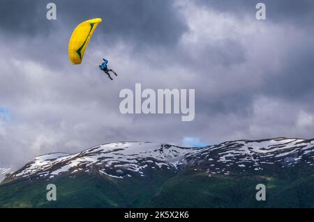 Ein Gleitschirm, der an einem bewölkten Tag über die Berge fliegt Stockfoto