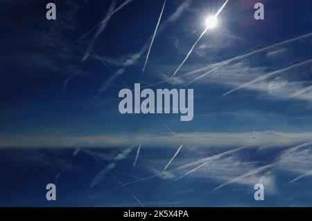 Schöner blauer Himmel mit Flugwegen und Wolken übersät Stockfoto