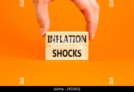 Symbol für Inflationsschocks. Konzept Worte Inflation Schocks auf Holzblöcke. Schöne orange Tisch orange Hintergrund. Geschäftsmann Hand. Geschäftliche Inflati Stockfoto