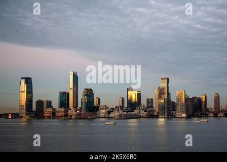 Am frühen Morgen des Herbstes fuhren Fähren den Hudson River hinauf, um Pendler aus New Jersey abzuholen und sie zur Arbeit in Manhattan zu bringen. Stockfoto