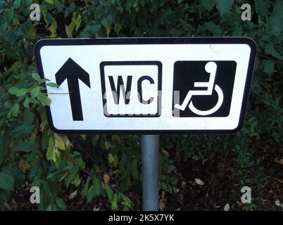 Behinderten-WC-Schild mit Richtungsanschrift in schwarz und weiß Stockfoto