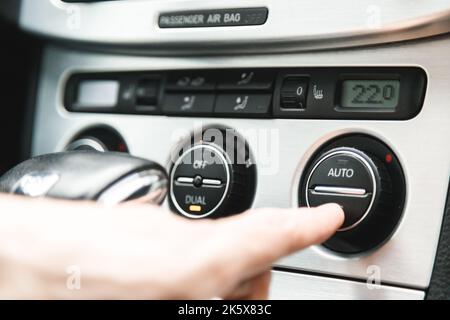 Die Hand drückt die Taste, um die Klimaanlage im Fahrzeug einzuschalten Stockfoto