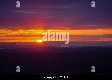 Sonnenuntergang mit crepuskulären Strahlen über dem EDF Energy Hinkley Point Kraftwerk Stockfoto