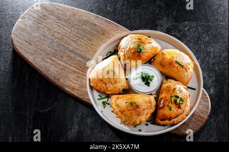 Zusammensetzung mit einem Teller aus im Ofen gebackenen Pierogi Stockfoto