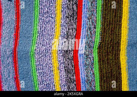 Verschiedene farbige Streifen auf der Strickstoffoberfläche. Textilien Retro Teppiche oder Teppiche. Die Textur des Stoffes ist eine Kombination mit der Geometrie von Stockfoto