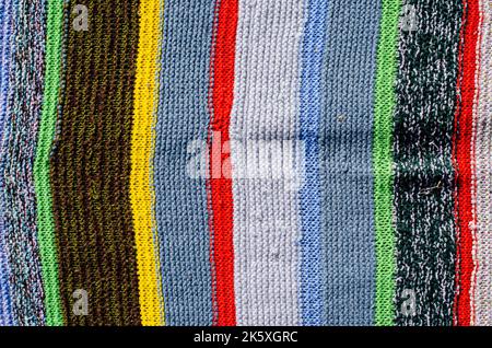 Verschiedene farbige Streifen auf der Strickstoffoberfläche. Textilien Retro Teppiche oder Teppiche. Die Textur des Stoffes ist eine Kombination mit der Geometrie von Stockfoto