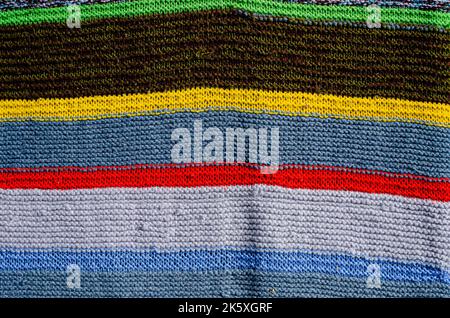Verschiedene farbige Streifen auf der Strickstoffoberfläche. Textilien Retro Teppiche oder Teppiche. Die Textur des Stoffes ist eine Kombination mit der Geometrie von Stockfoto