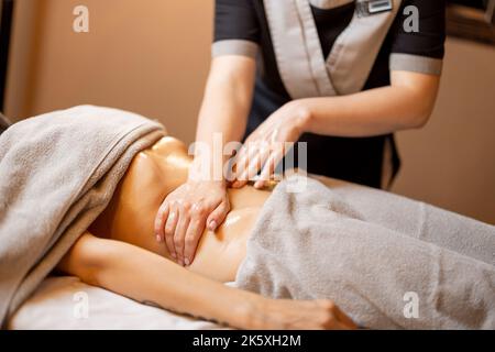 Masseuse führt eine professionelle Bauchmassage für eine Frau durch Stockfoto