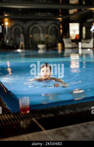 Mann, der im Pool im Spa Resort schwimmt Stockfoto