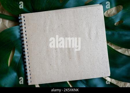 Leerer Spiralnotepad auf grünen Sommerblättern. Leere Papierseite Notizbuch, flach liegend, Kopierplatz Stockfoto
