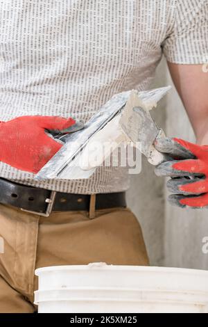 Kalkputz auf einem Spachtel, Reparatur und Dekoration arbeiten mit Kalkputz, zwei schmutzigen Spachtel, Kalkputz im Eimer. Stockfoto