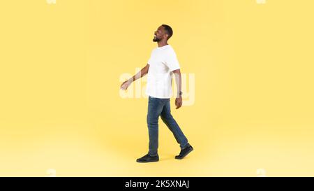 Sorgloser Afroamerikanischer Mann, Der Lächelnd Zur Seite Schaut, Gelber Hintergrund Stockfoto