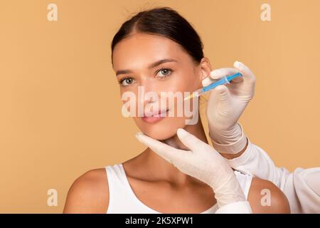 Lippenvergrößerung Konzept. Doktor Hände in Handschuhe mit Spritze in der Nähe des weiblichen Gesichts, glückliche Frau erhalten Schönheitsspritze Stockfoto