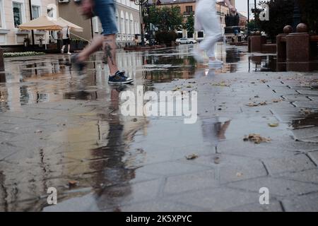 Straßen der Stadt nach starkem Regen. Barfuß auf Gehwegen mit Pfützen und Reflexionen Stockfoto