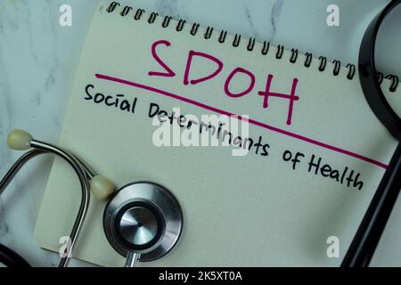 Konzept von SDOH - Soziale Determinanten der Gesundheit schreiben auf ein Buch isoliert auf Holztisch. Stockfoto