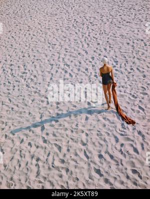 Rückansicht Porträt einer Frau im einteiligen Badeanzug beim Strandspaziergängen, Toni Frisell Collection, Dezember 1948 Stockfoto