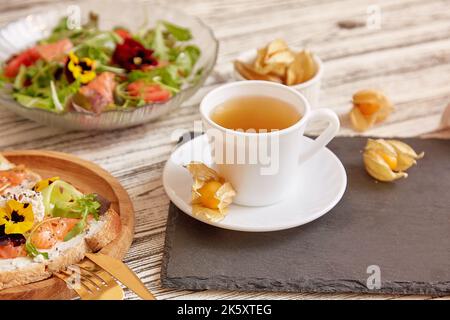 Gesunder Frühstückssalat und Toast mit geräuchertem Lachs, Gemüse, Gemüse und essbaren Blumen Stockfoto