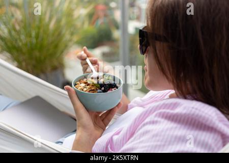 Junge Frau, die Chia-Pudding mit Nüssen und Beeren isst Stockfoto