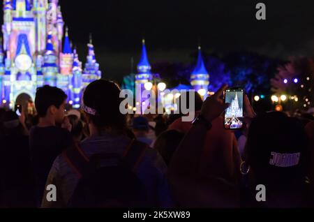 Eine Person, die in Disney World in Orlando, Florida, ein Foto des Disney Castle auf ihrem Handy auffängt. Stockfoto