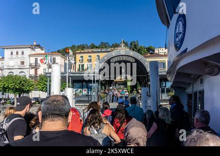 Die Passagiere machen sich bereit, von einer Fähre am Comer See in der Stadt Bellagio, Italien, auszusteigen, während Menschenmassen an Bord warten, Stockfoto