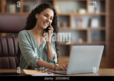 Positive hübsche junge Geschäftsfrau mit Telefonanruf Stockfoto