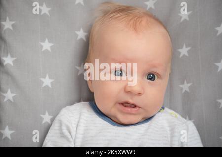 Porträt eines überraschten Neugeborenen, Nahaufnahme. Schnitt Kind mit blauen Augen, Blick auf die Kamera. Gesichtsausdruck. Stockfoto