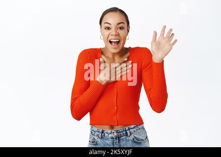 Enthusiastische afroamerikanische Frau, die die Hand hebt, sich nennt, vorstellt oder freiwillig, ihre ich-Geste, die auf weißem Hintergrund steht Stockfoto