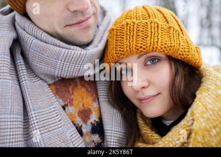 Nahaufnahme einer jungen Frau, die den Kopf auf der Schulter des Partners ruht und lächelt, während sie den Winterurlaub für Paare genießt Stockfoto