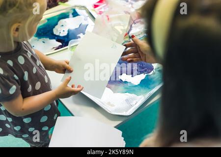 Lassen Sie mich Ihnen zeigen, wie man malt - ein Lehrer hilft Vorschulkinder, im Kindergarten zu malen. Hochwertige Fotos Stockfoto