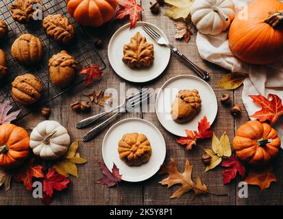 Draufsicht auf kleine herbstliche Kürbis-Gewürzkuchen auf Tellern. Stockfoto