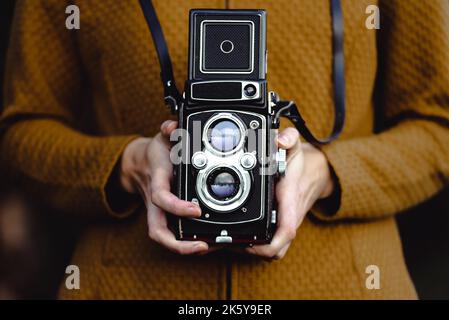 Eine junge Frau hält eine Retro-120-mm-Rollkamera. Stockfoto