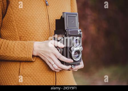 Eine junge Frau hält eine Retro-120-mm-Rollkamera. Stockfoto