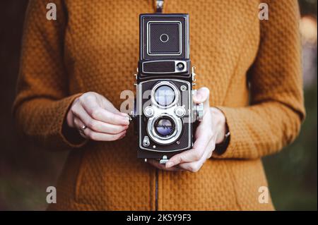 Eine junge Frau hält eine Retro-120-mm-Rollkamera. Stockfoto