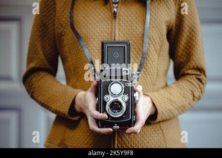 Eine junge Frau hält eine Retro-120-mm-Rollkamera. Stockfoto